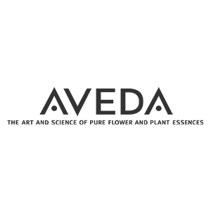 Logo del marchio Aveda con la parola "AVEDA" in lettere maiuscole nere e lo slogan sottostante su sfondo bianco.