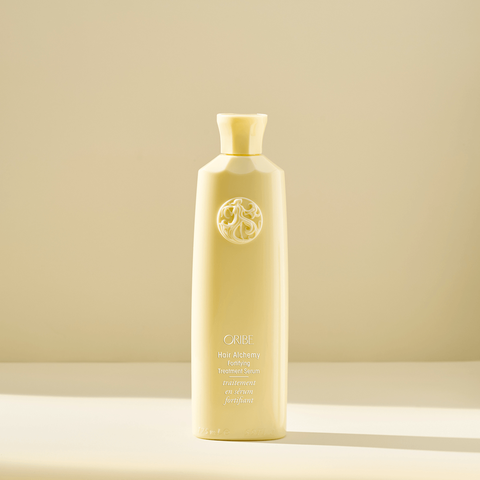 Flacone color crema della lozione corpo Chanel n. 5 con logo circolare minimalista in rilievo, su sfondo neutro.