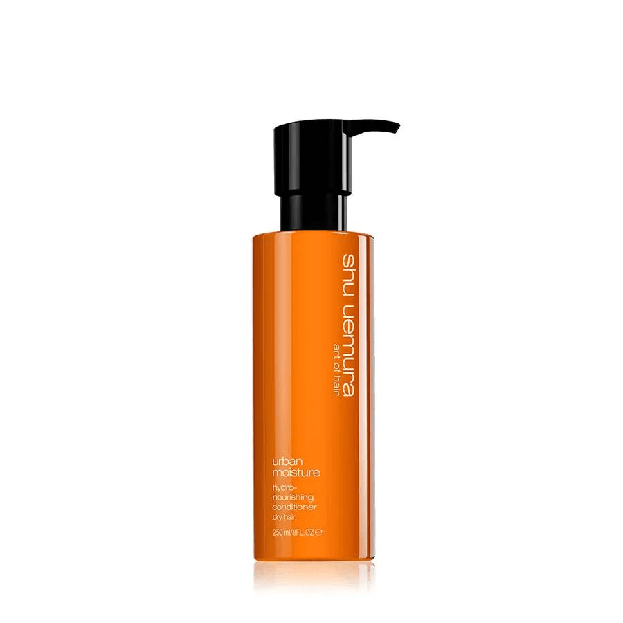Una bottiglia di balsamo per capelli Shu Uemura Urban Moisture con corpo arancione e dosatore a pompa nero su sfondo bianco.