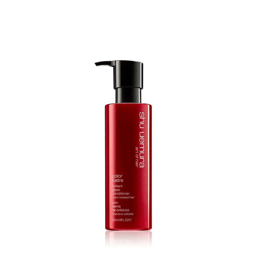 Una bottiglia di balsamo Shu Uemura Color Lustre di colore rosso con dosatore a pompa nero su sfondo bianco.
