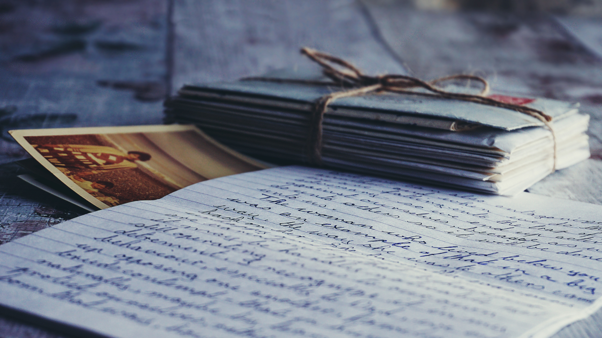 Stack of notebooks and a photo resting on handwritten pages outdoors.