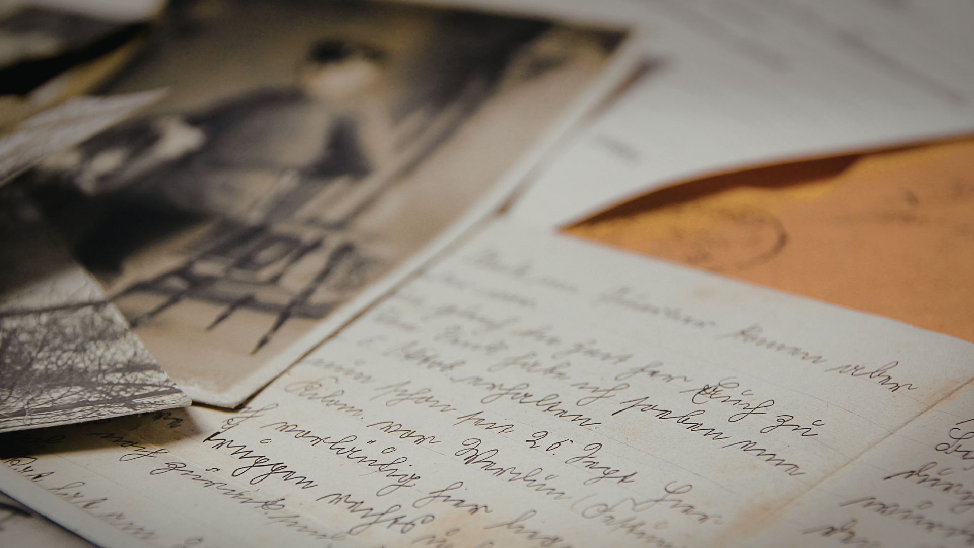 Open notebook with handwritten notes beside scattered black-and-white photographs