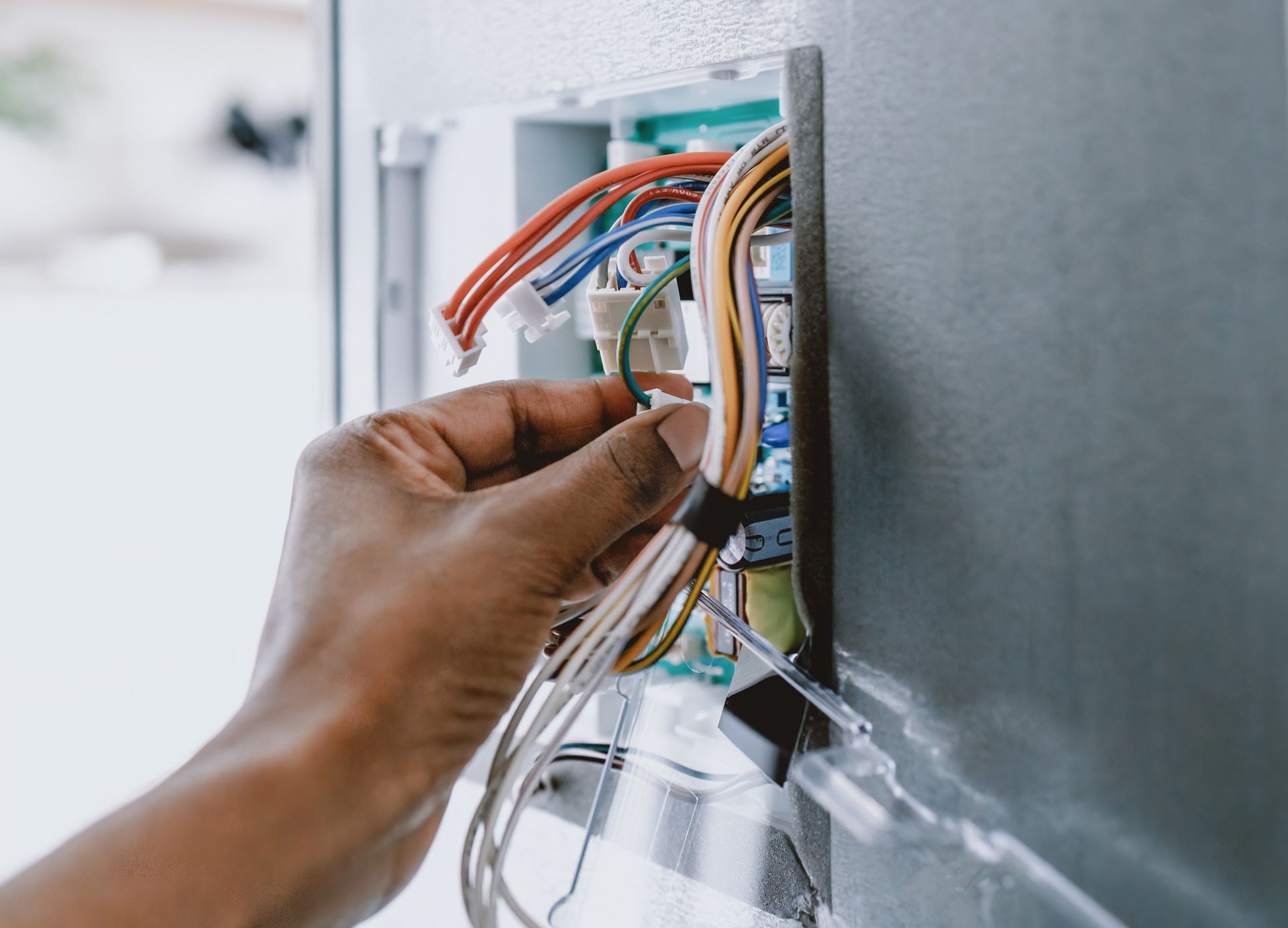A person is working on an electrical box with a screwdriver.