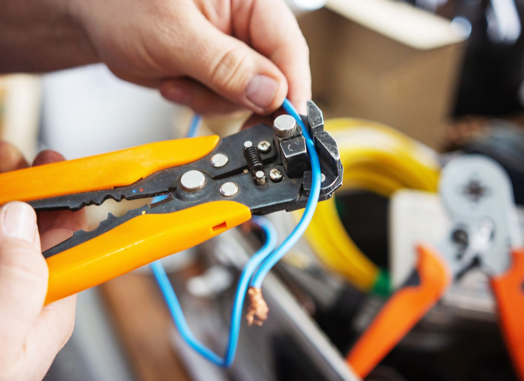A person is using a wire stripping tool to cut a wire