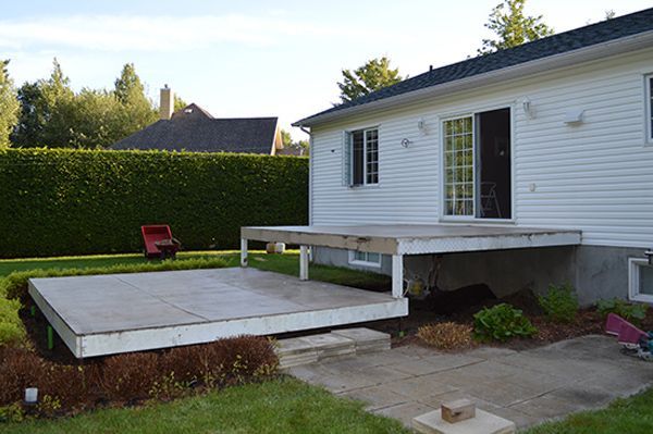 Une maison blanche avec une grande terrasse en bois devant elle