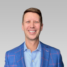 Smiling man in a blue blazer and light blue shirt against a gray background