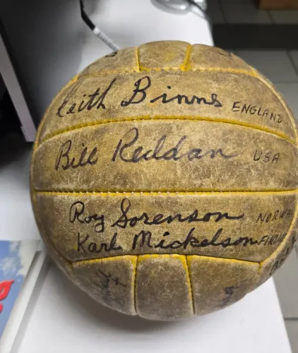 Vintage signed leather football with handwritten signatures on a display stand