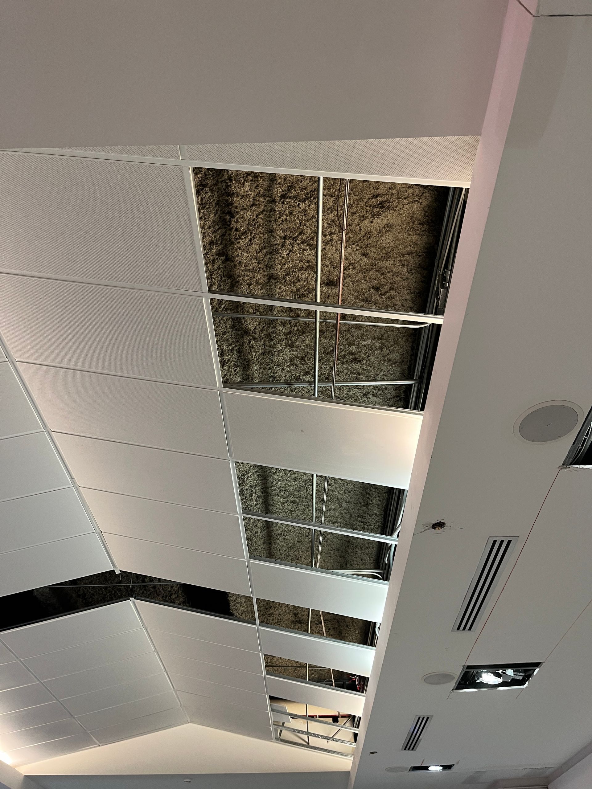 Open ceiling with missing tiles and visible building systems