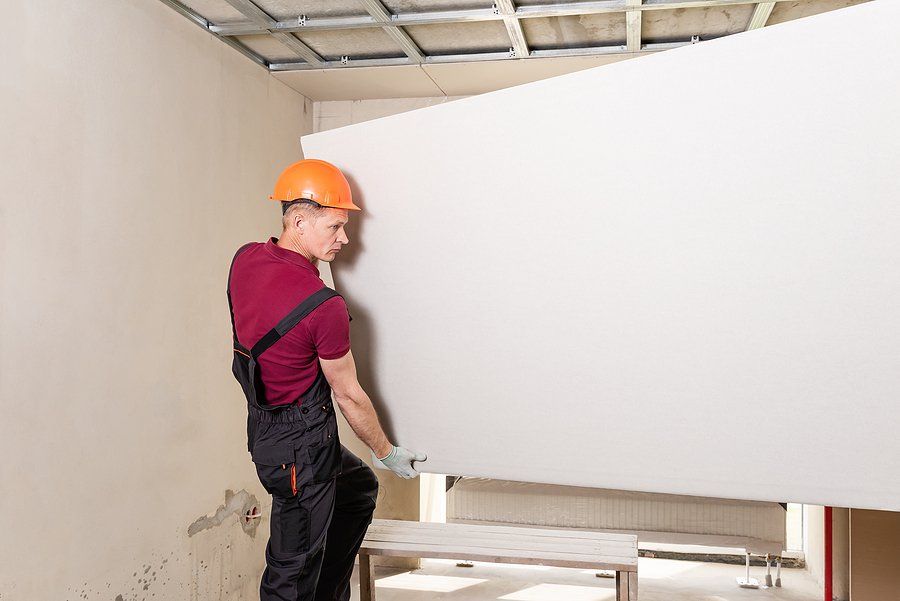 experienced drywall crew members lifting a panel into place inside commercial space