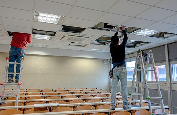 acoustic panels being inserted by workers for drop ceiling