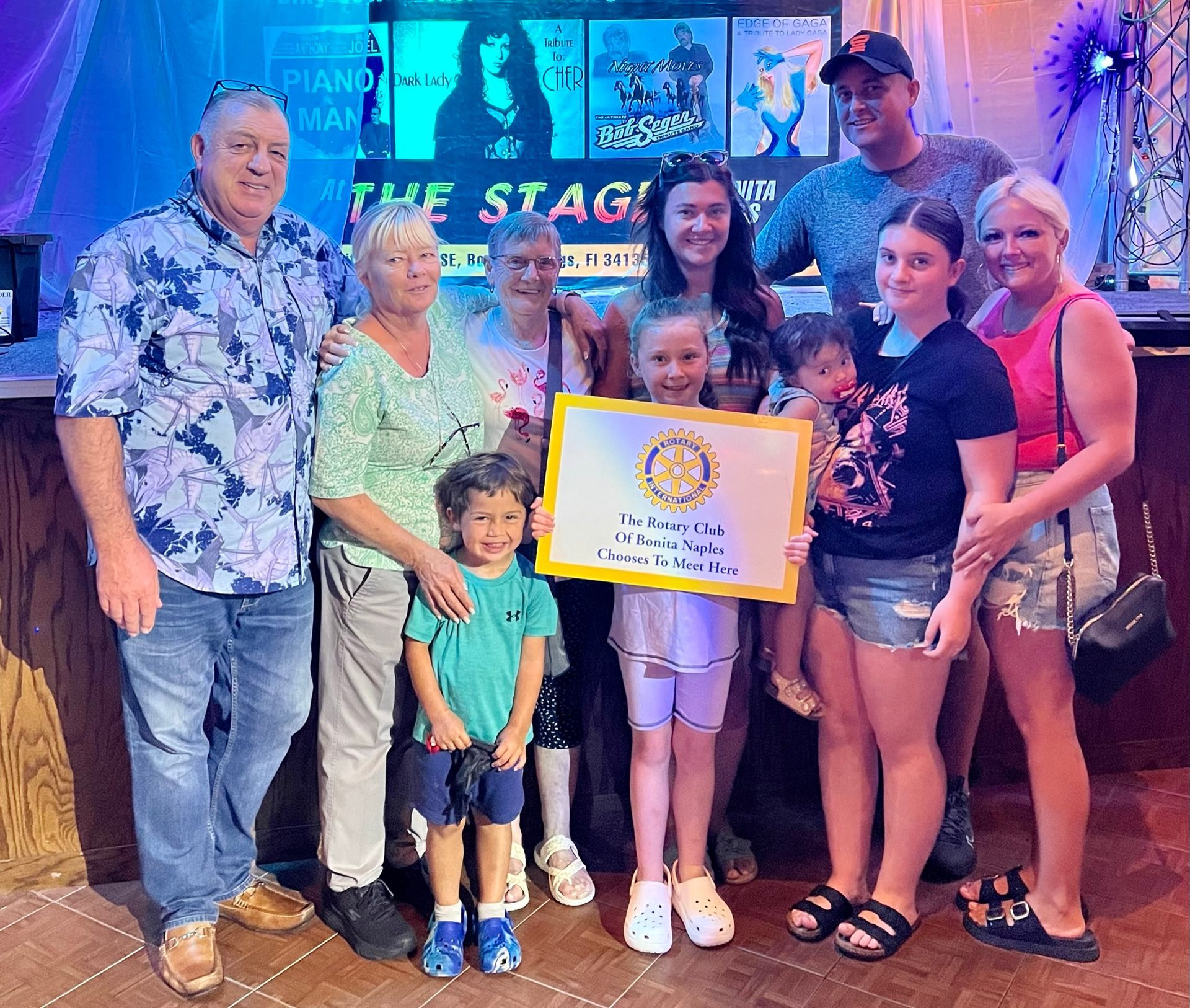 A group of people are posing for a picture in front of a sign that says the stage