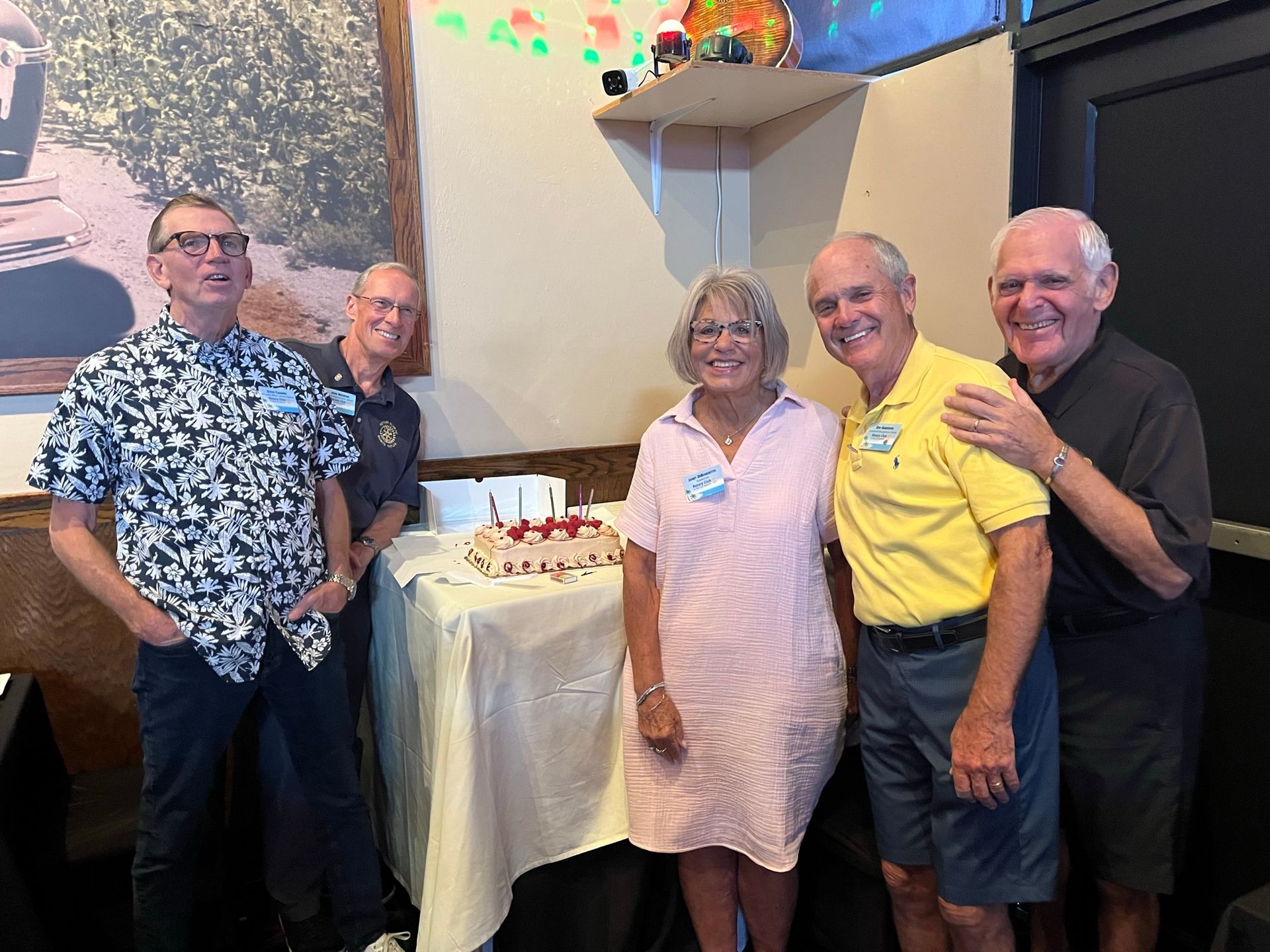 A group of people are posing for a picture in front of a cake.