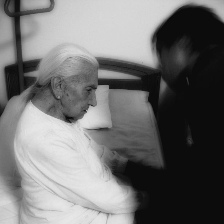 A black and white photo of an elderly woman sitting in a bed