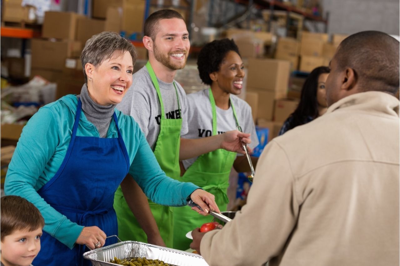 A group of people are serving food to a man in a warehouse.