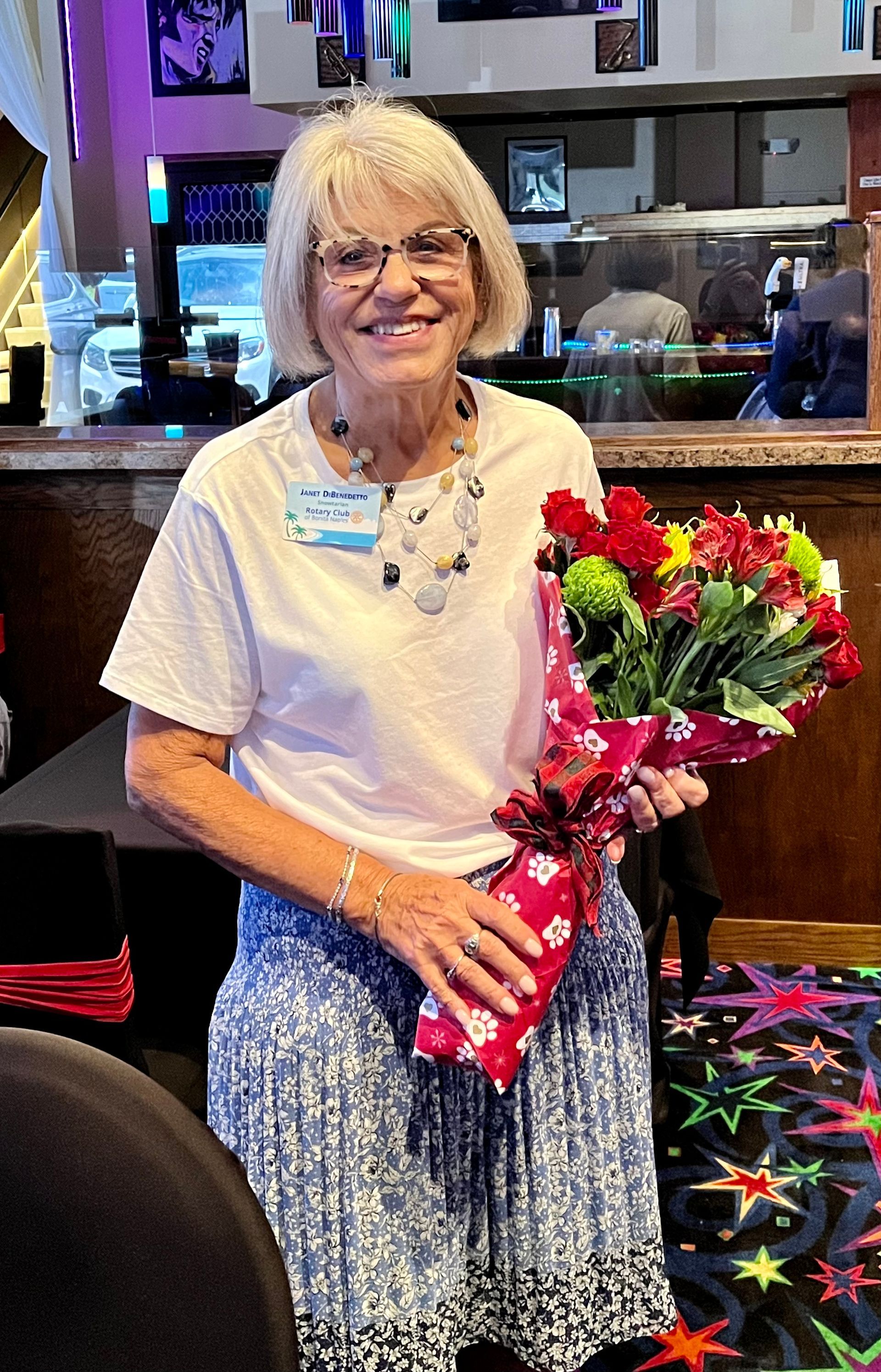 A woman is holding a bouquet of flowers in a restaurant.