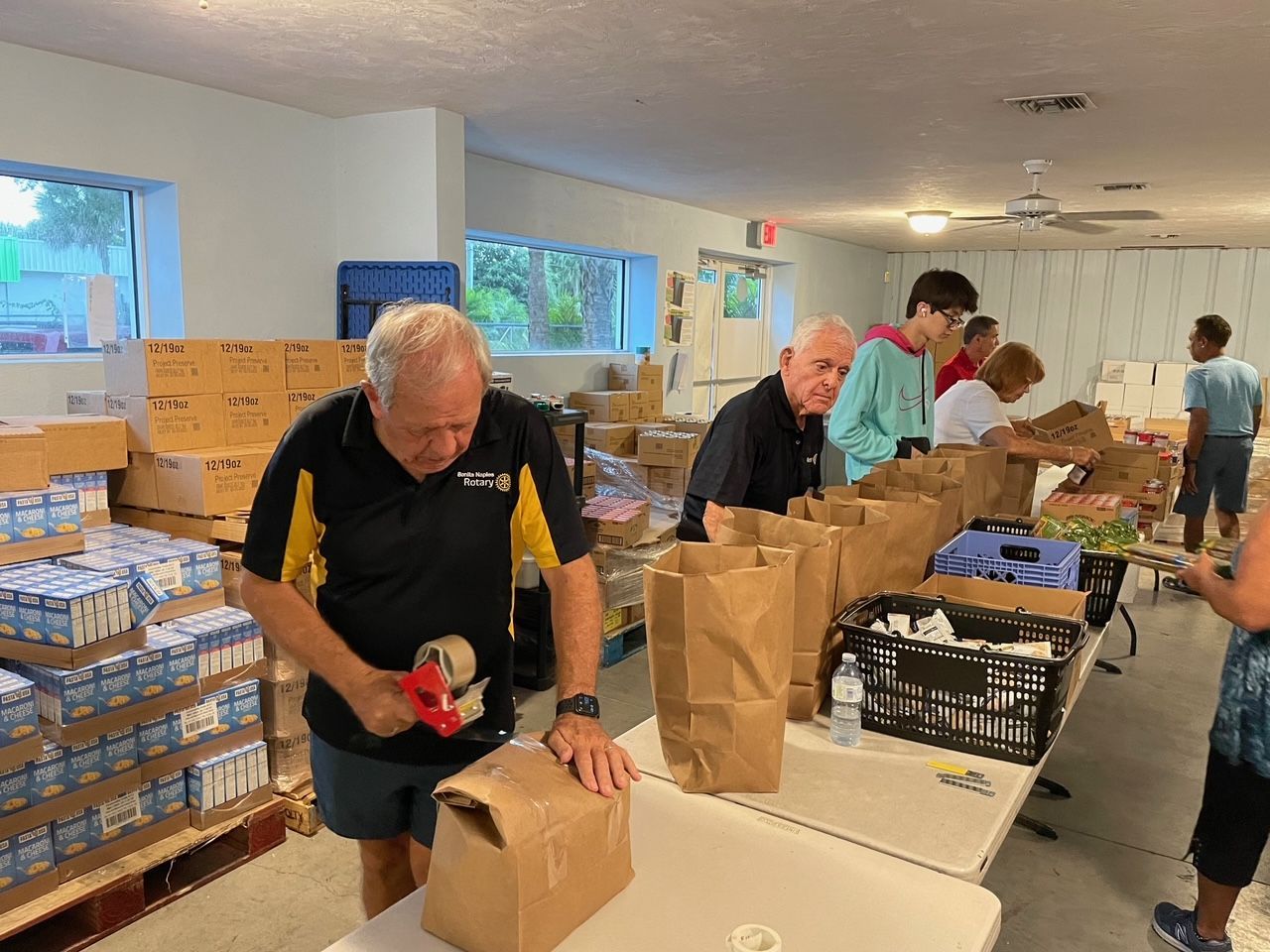 A group of people are packing bags of food in a room.