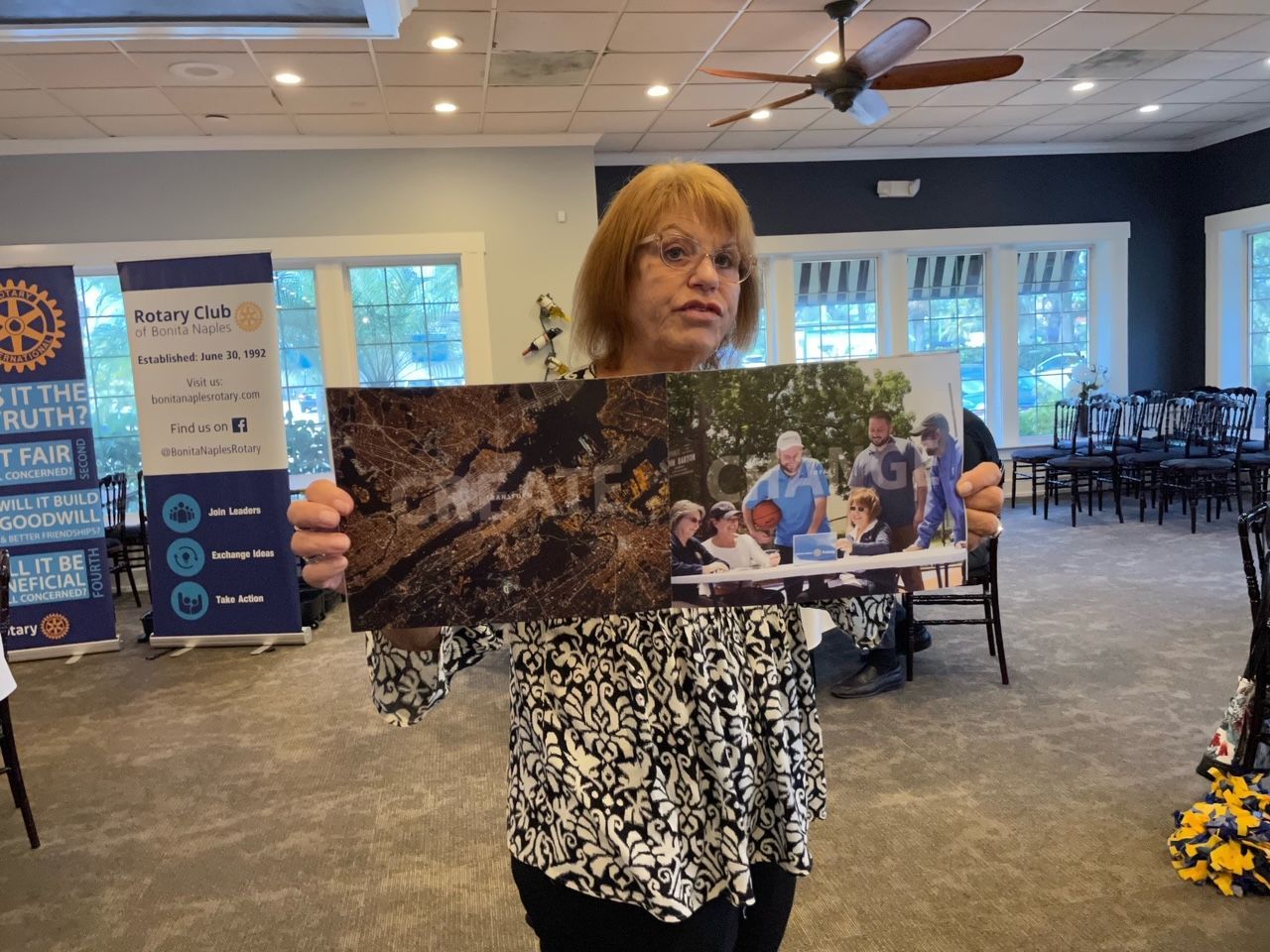 A woman is holding a picture of a group of people in a room.