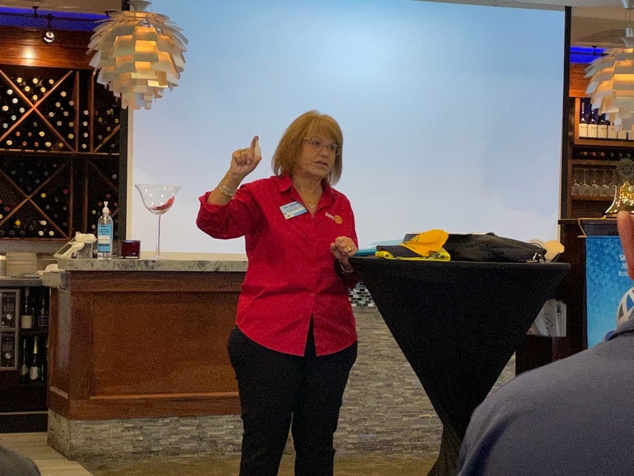 A woman in a red shirt is giving a thumbs up