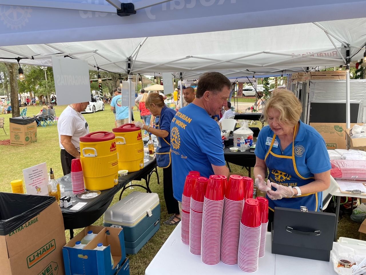 A group of people are standing around a table under a tent.