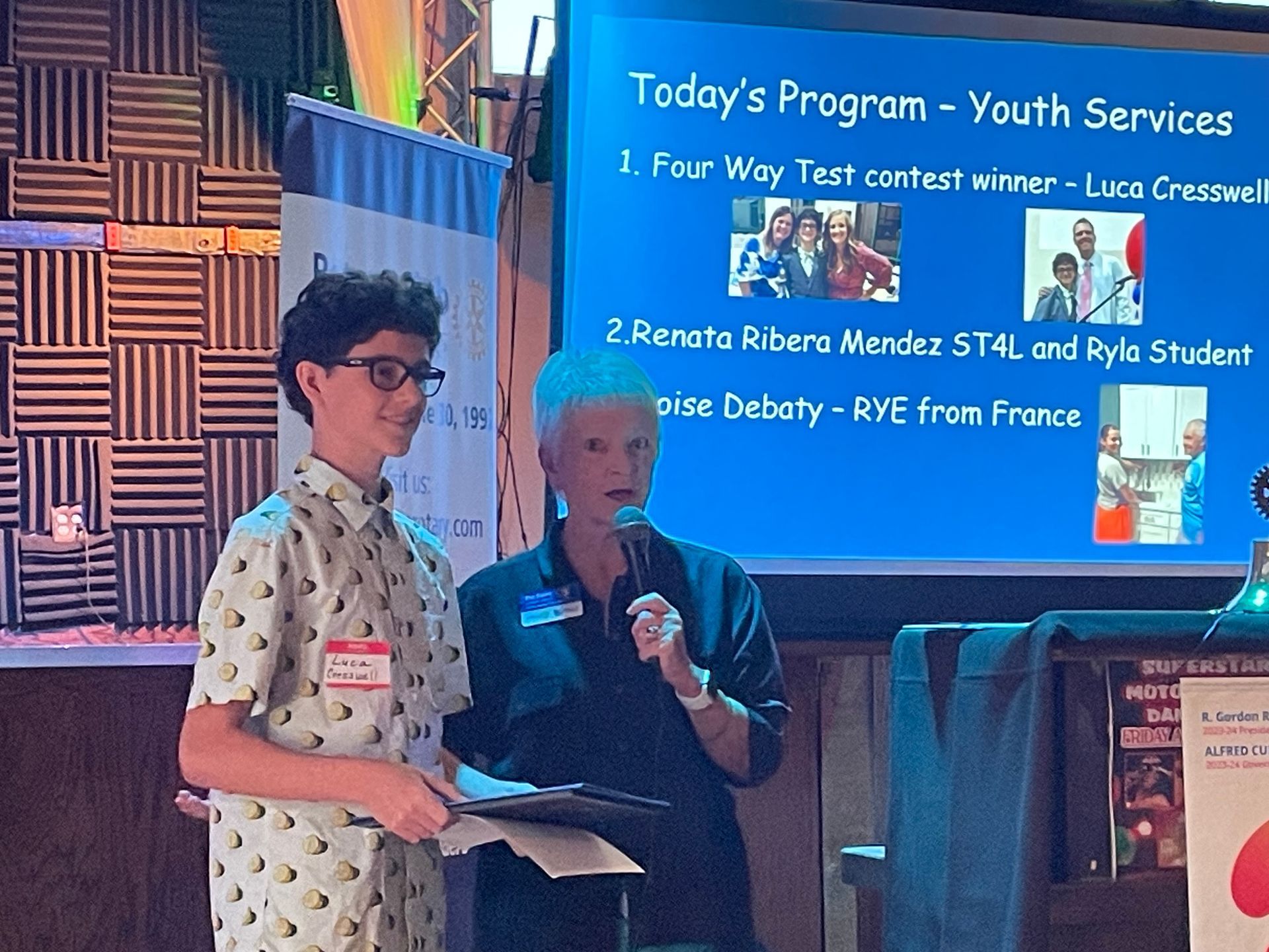 Two people standing in front of a screen that says today 's program youth services