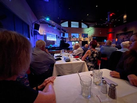 A group of people are sitting at tables in a restaurant watching a show.