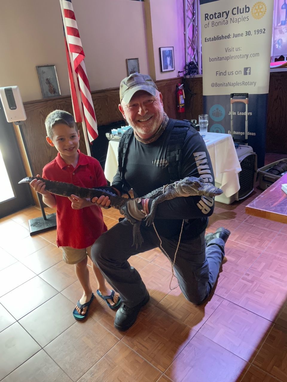 A man is kneeling down next to a boy holding a snake.