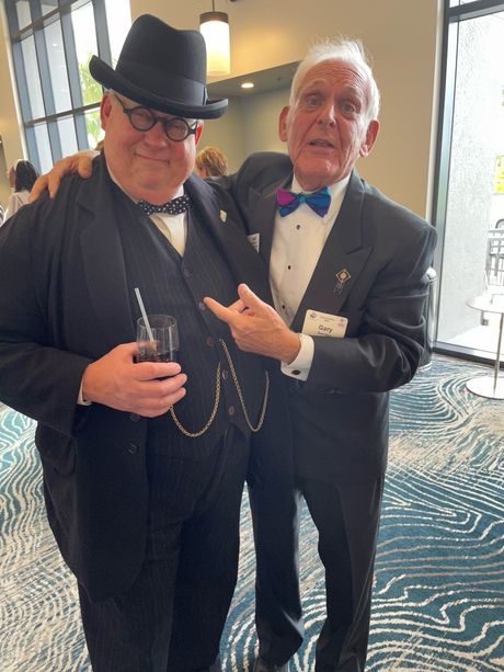 Two men in suits and hats are posing for a picture