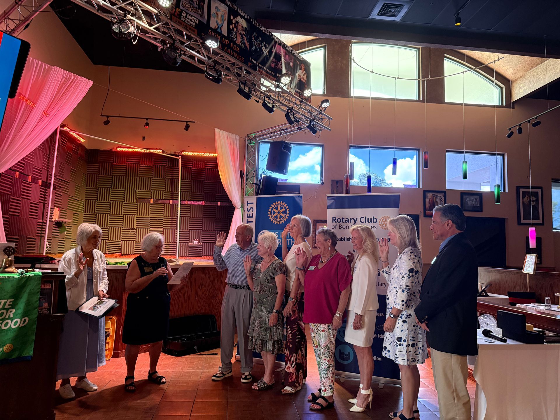 People standing in a warmly lit hall near a presentation screen and booth displays