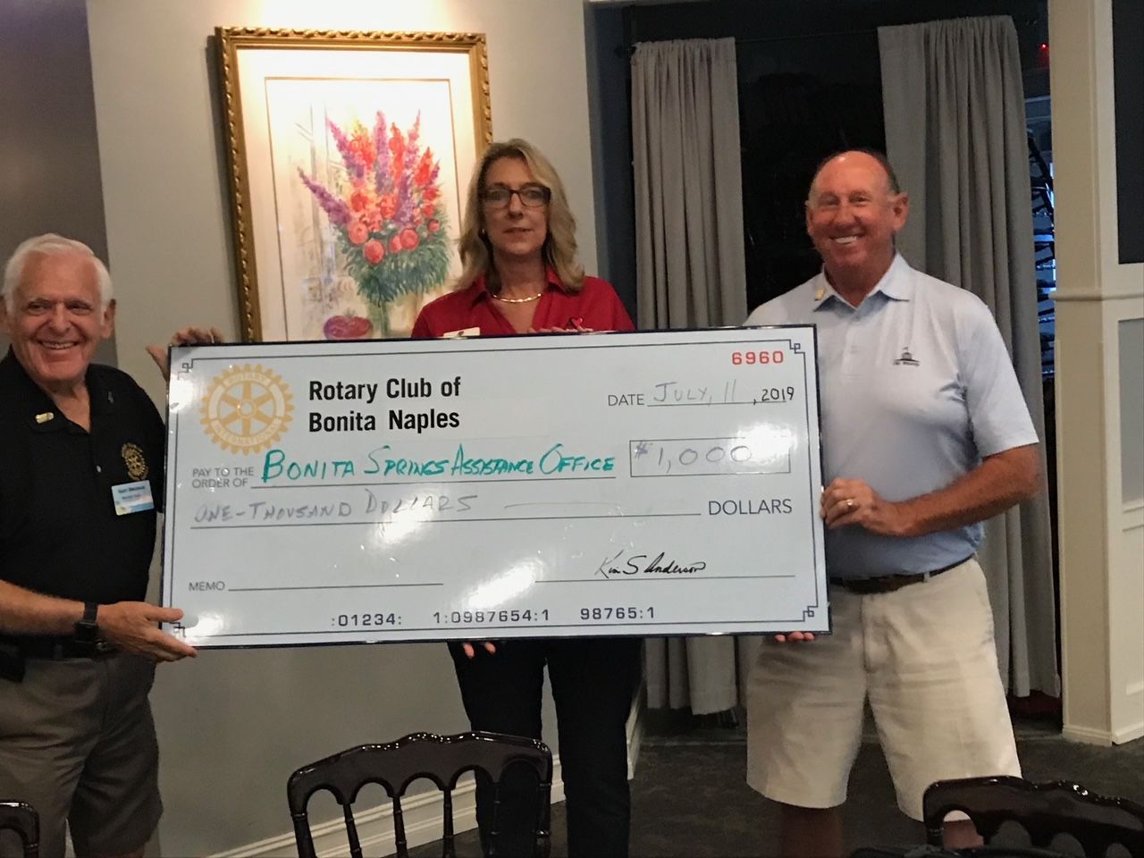 Two men and a woman holding a rotary club check