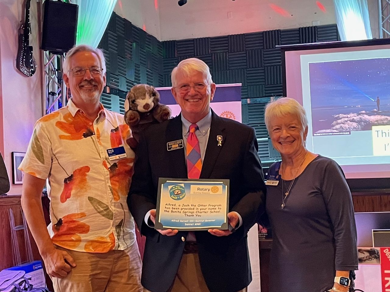 A man in a suit is holding a certificate while standing next to two women.