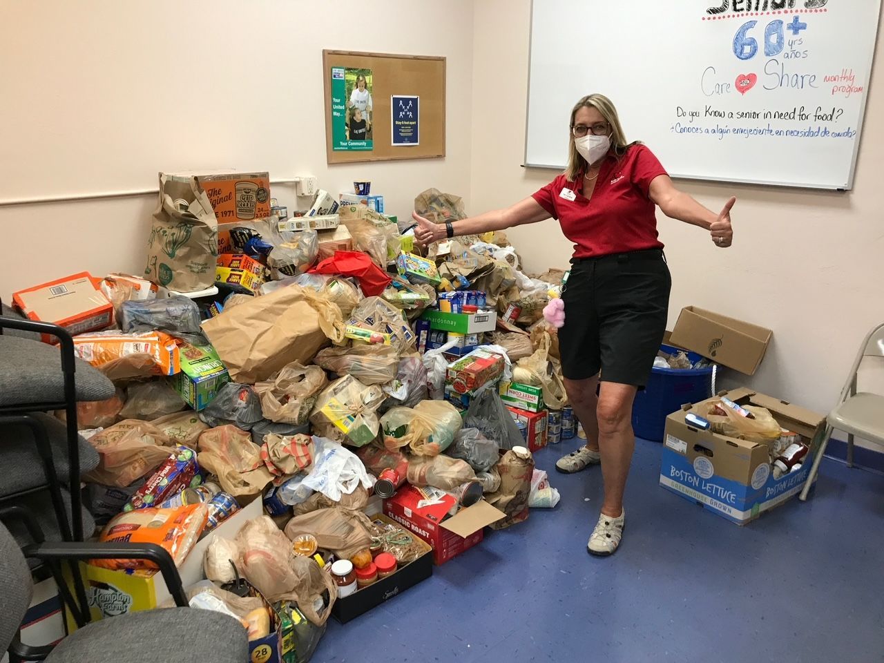 A woman wearing a mask is standing in front of a pile of food.