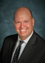 A man in a suit and tie is smiling for the camera.