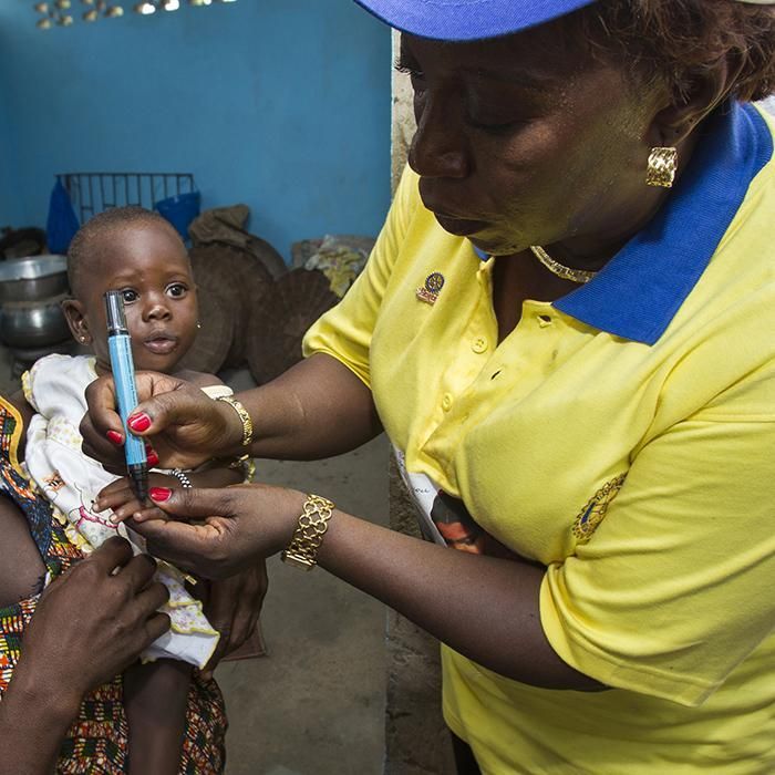 A woman in a yellow shirt is holding a baby