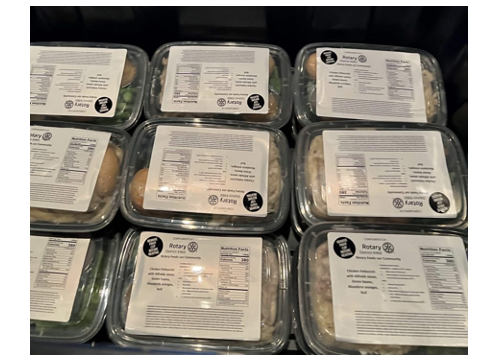 A row of plastic containers filled with food with labels on them.
