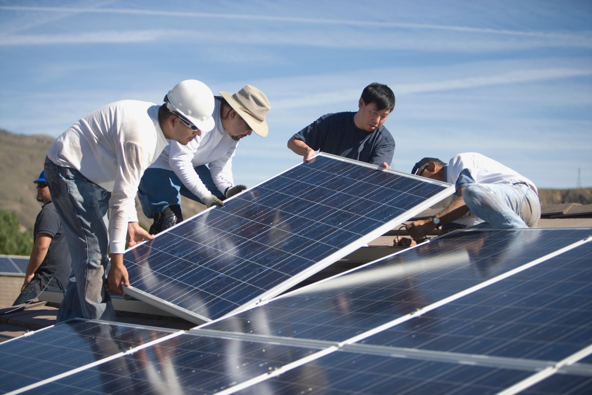 A group of men are installing solar panels on a roof.