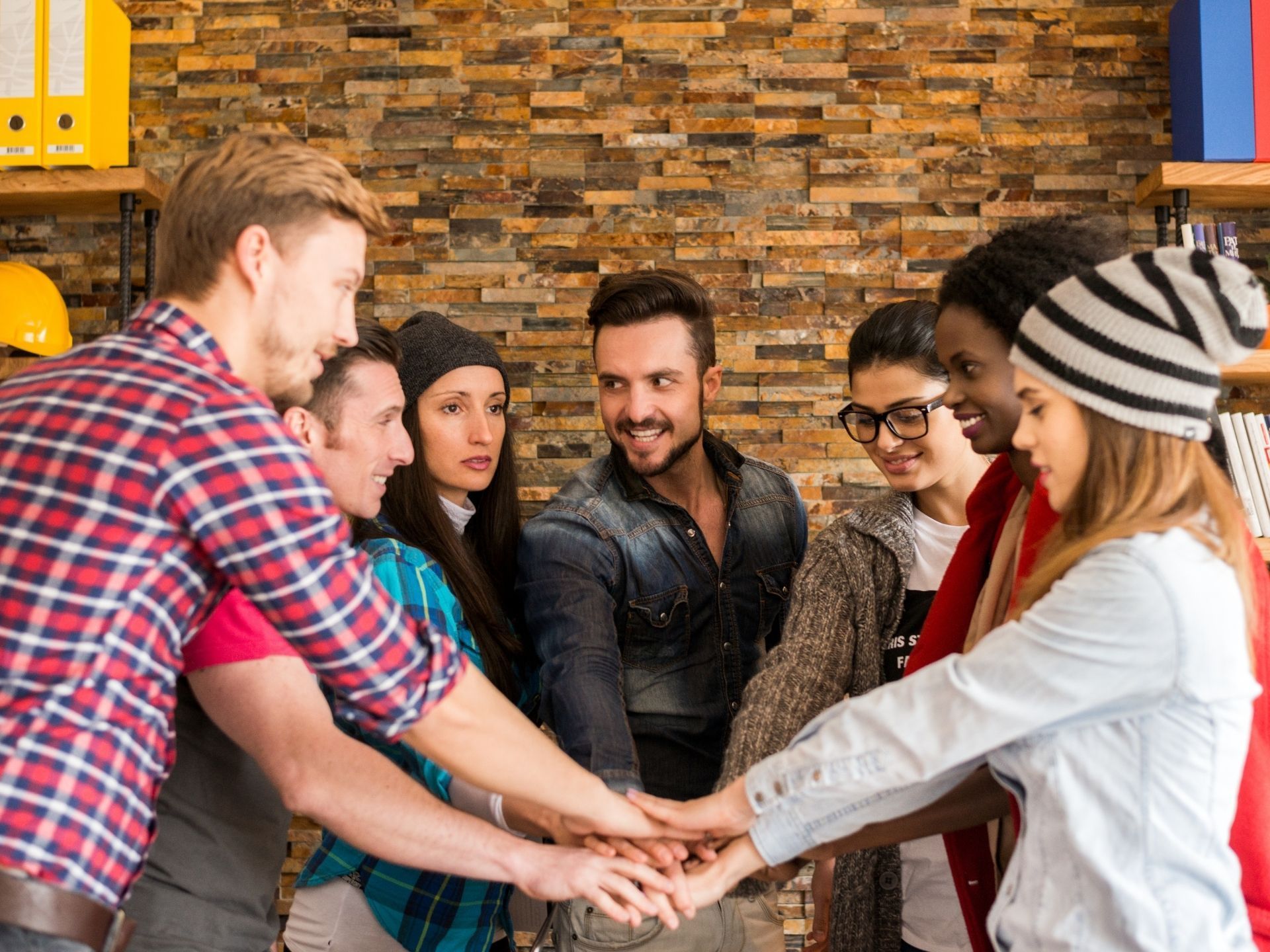A group of people are putting their hands together in a circle.