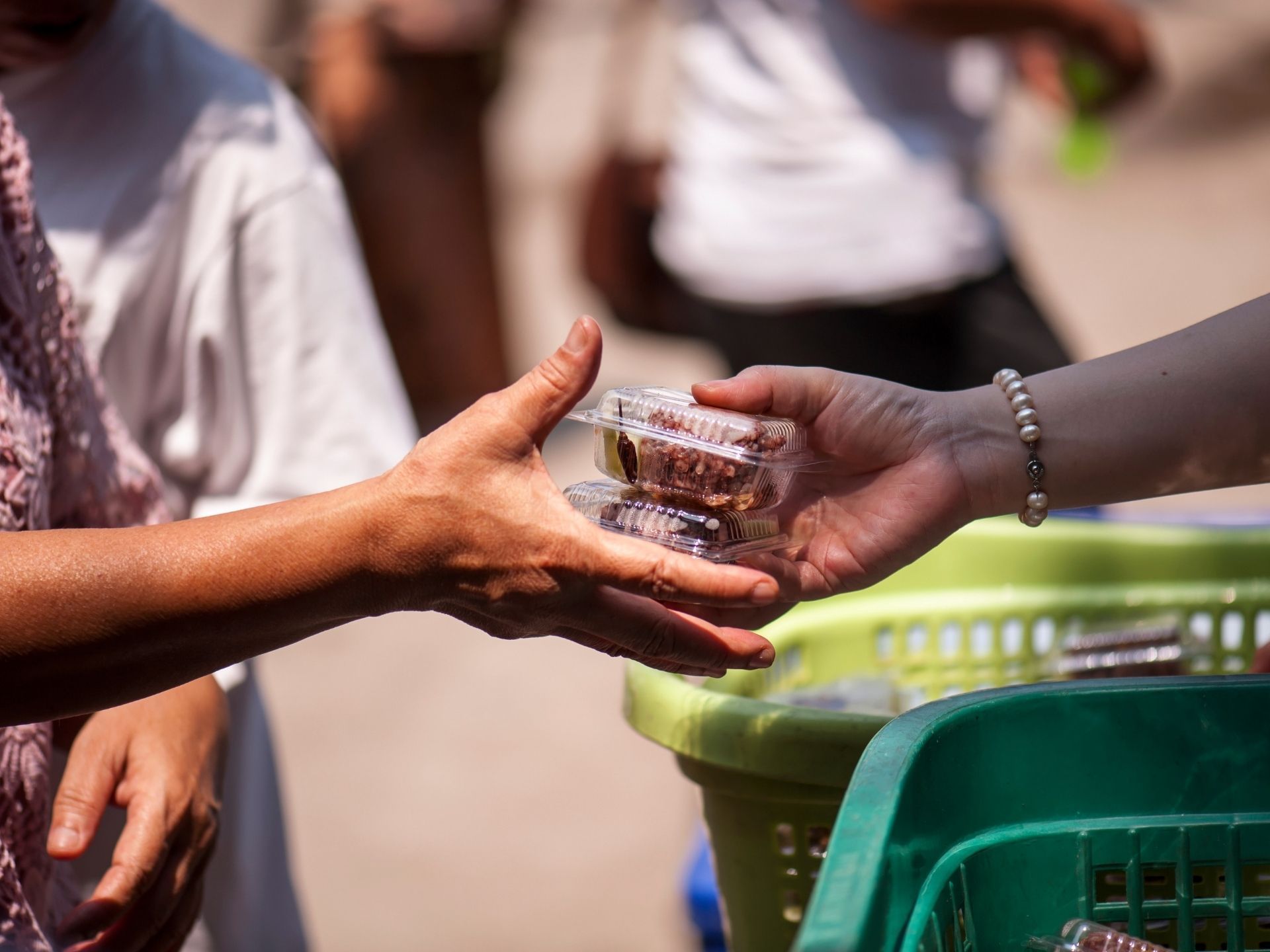 A person is giving a container of food to another person.