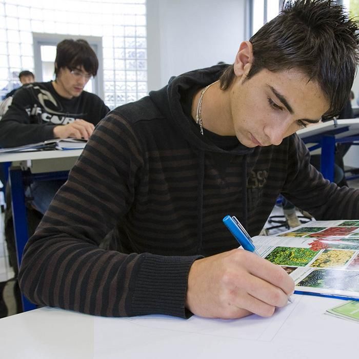A man in a striped sweater is writing on a piece of paper