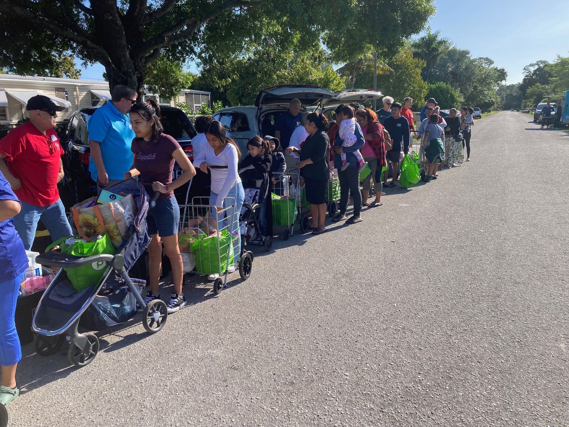 A group of people are standing in a line holding shopping carts.