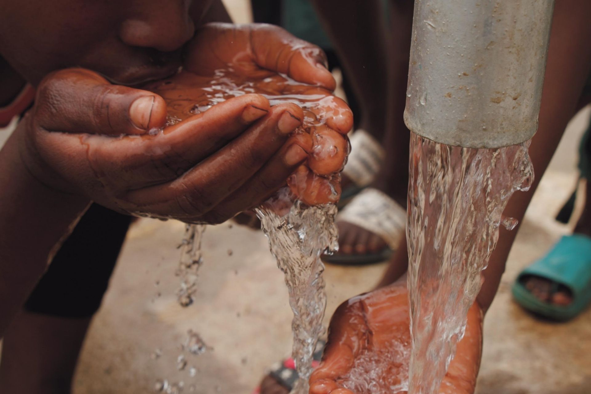 A child is drinking water from a well.