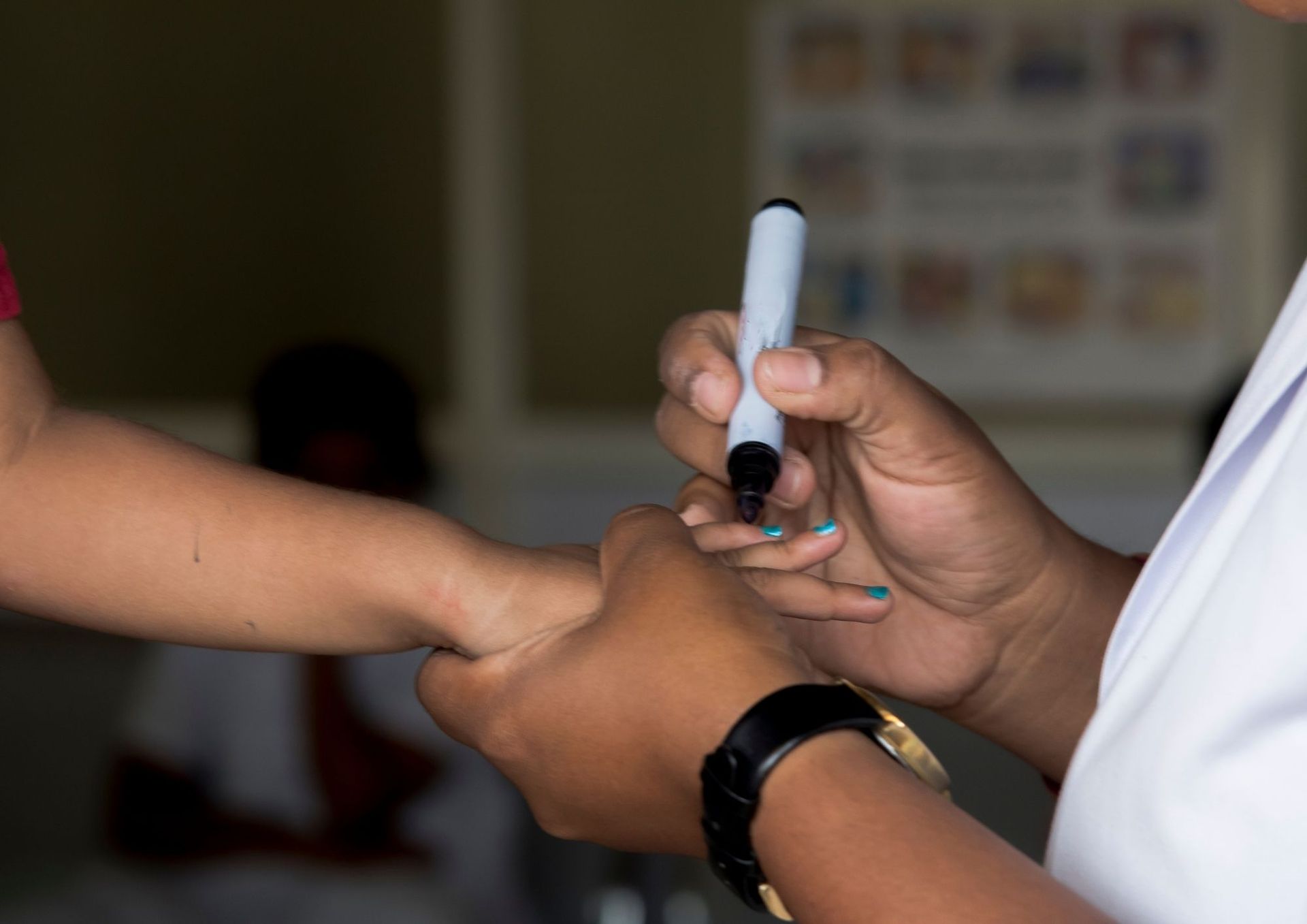 A person is holding a marker over another person 's hand.