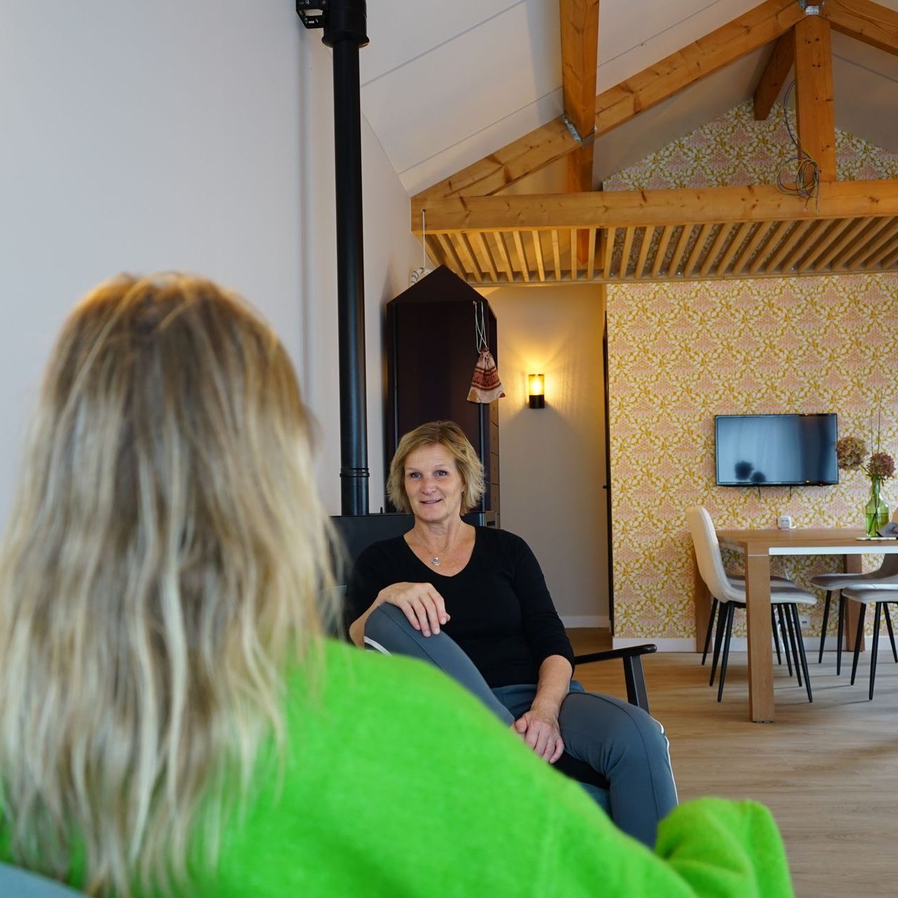Twee vrouwen praten in een gezellige praktijkruimte.