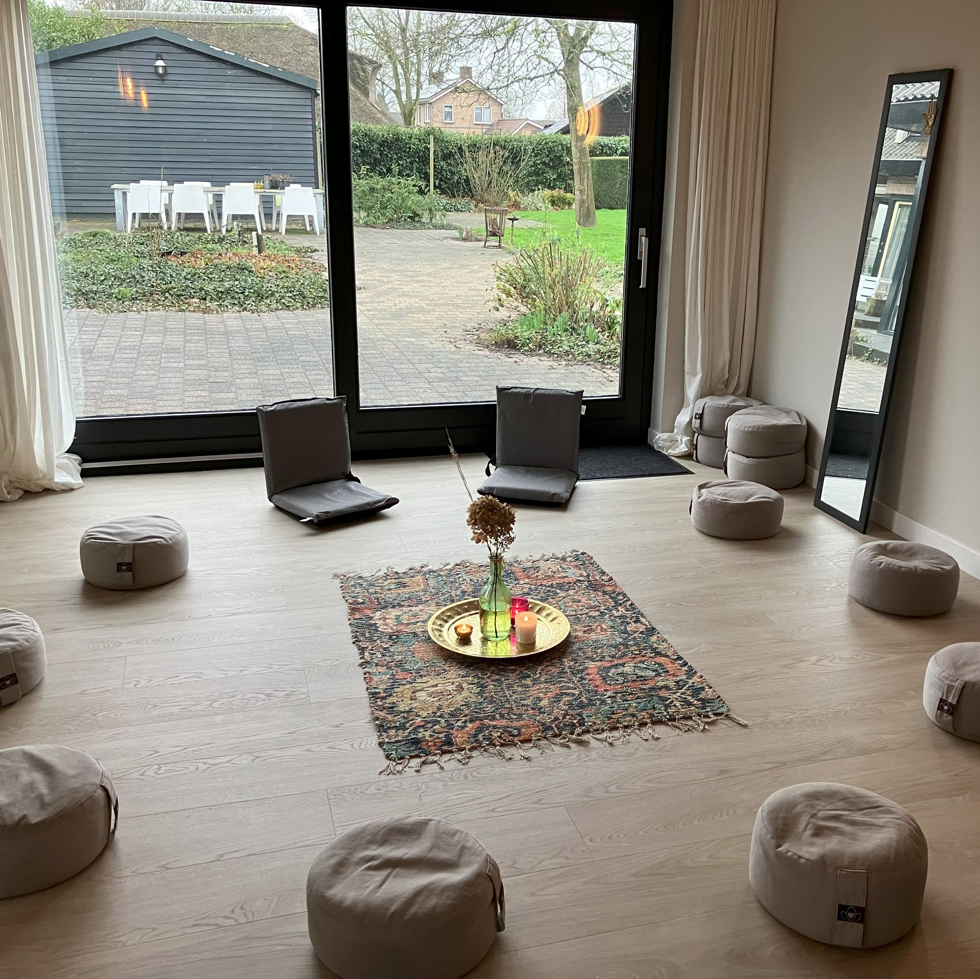 Lichte, gezellige praktijkruimte met kussentjes en stoeltjes.