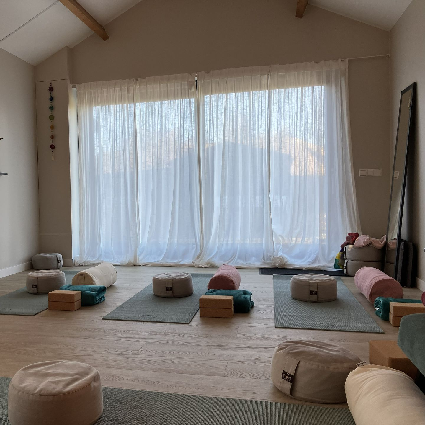 Interieur van een yogastudio met een groot raam met transparante gordijnen.