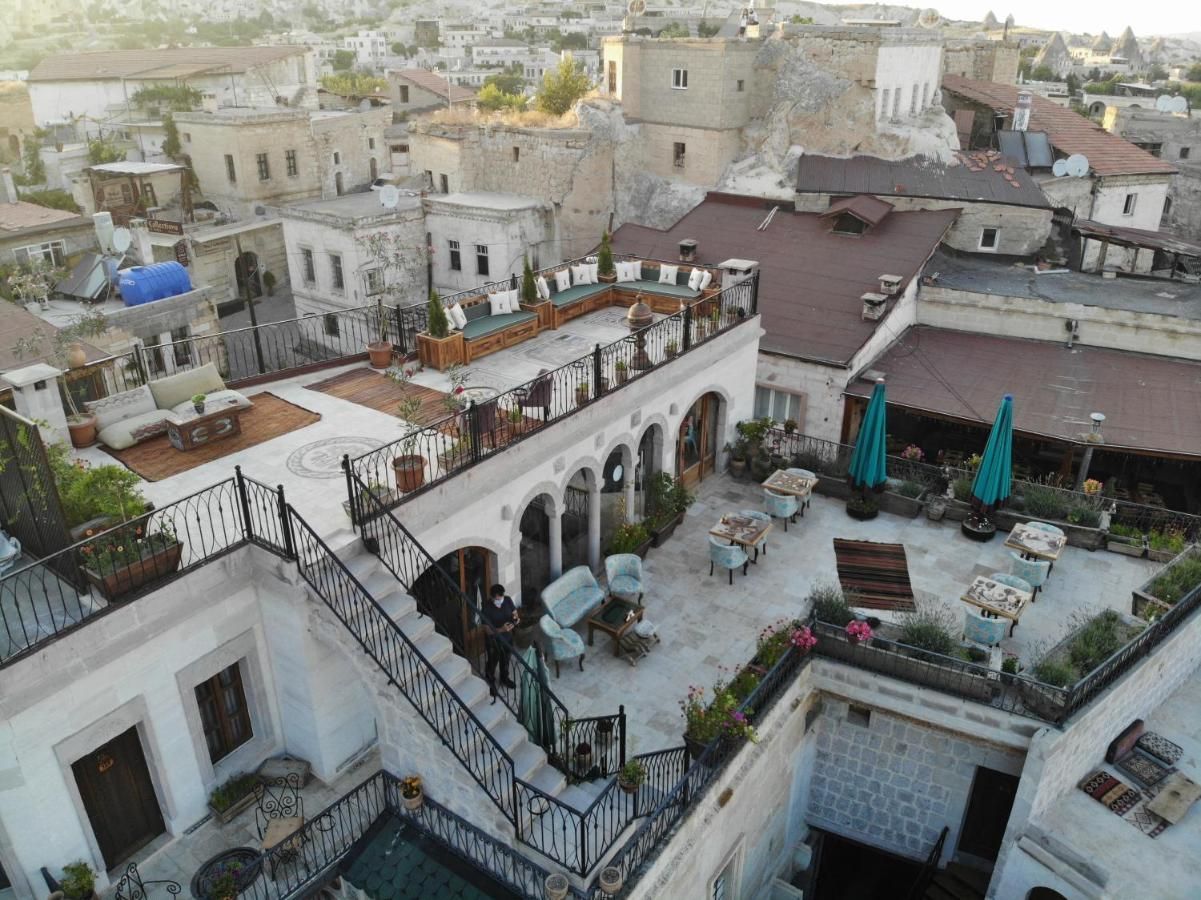 Rooftop restaurant in Cappadocia, Turkey. White buildings with outdoor seating, stairs, and umbrellas.
