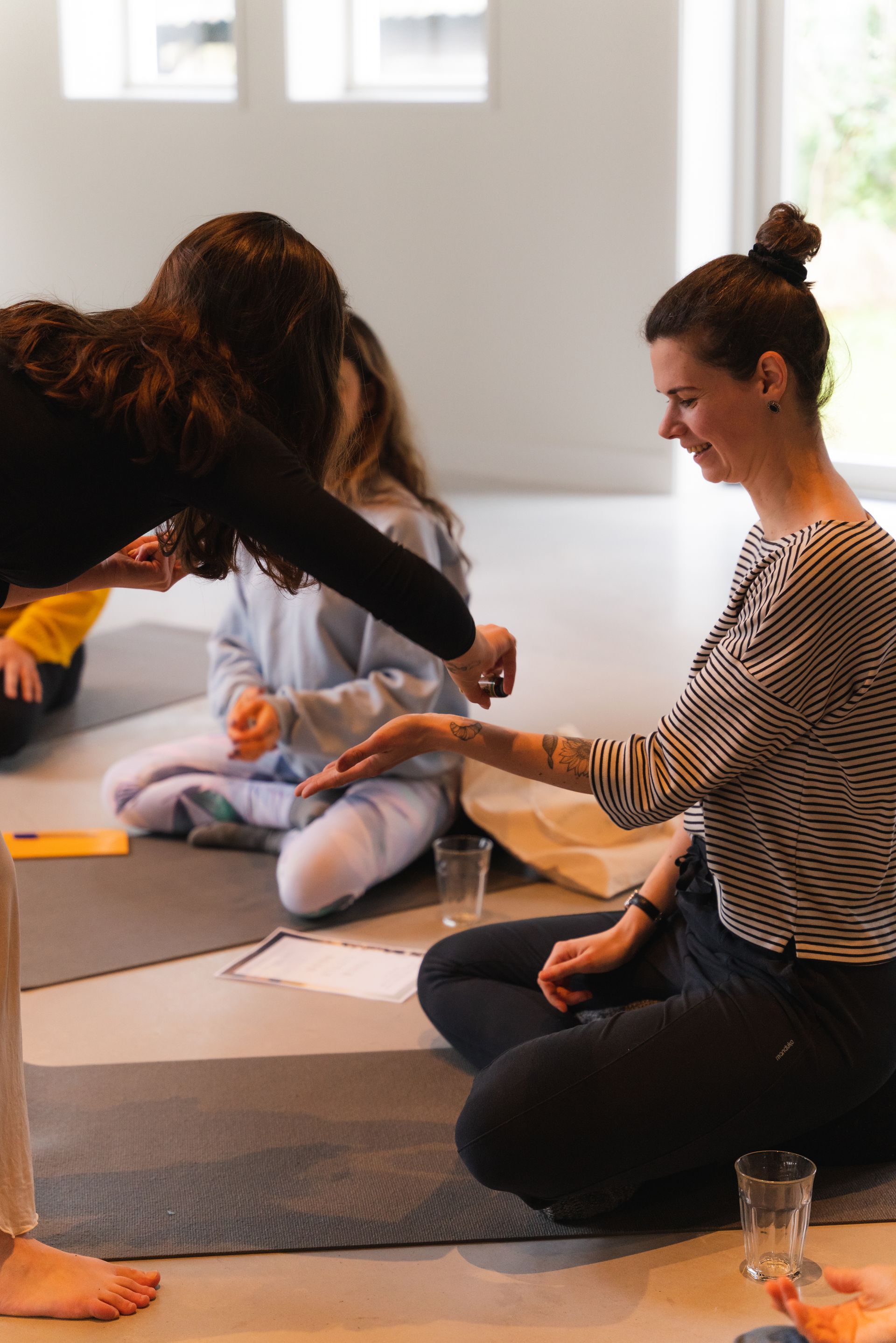 Woman offering hand, other person reaching toward it; seated indoors.