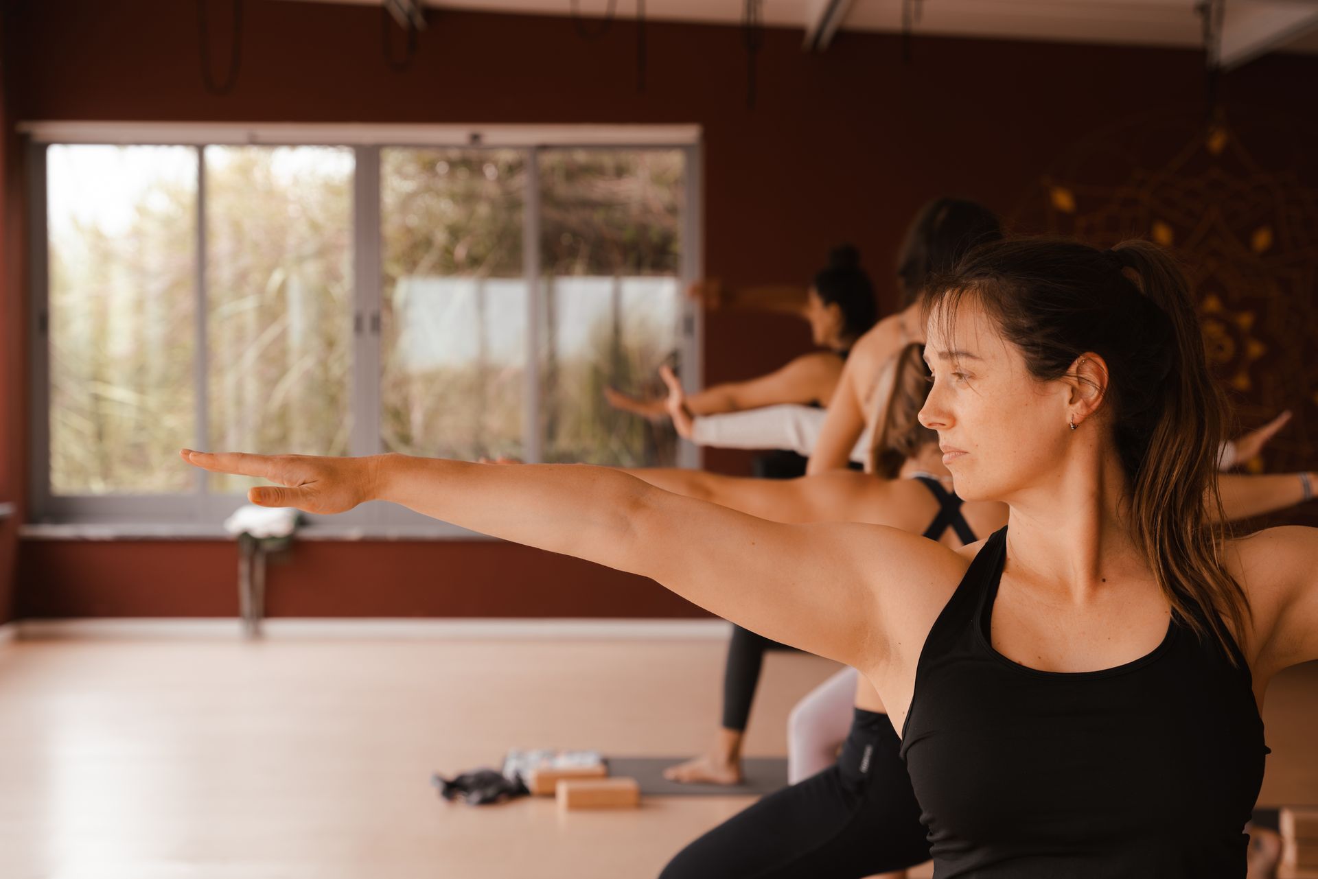 People practicing yoga in a studio, with arms extended.