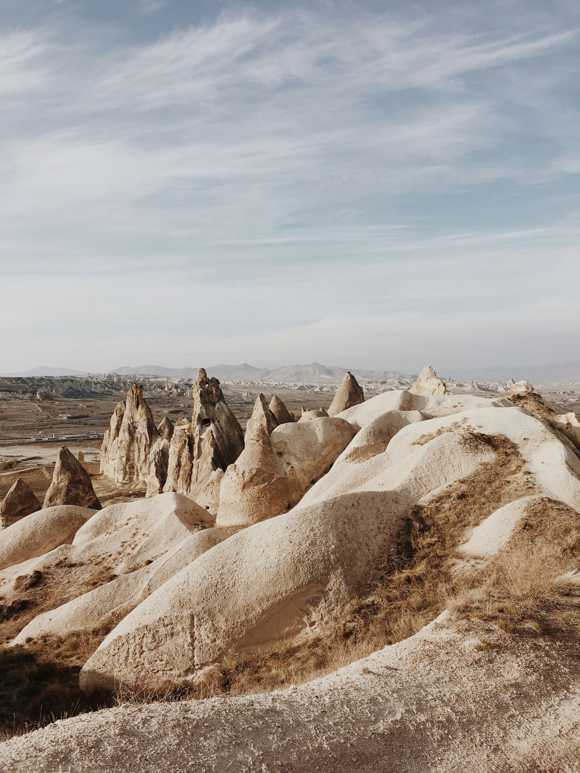 Eroded rock formations in a desert landscape under a cloudy sky.