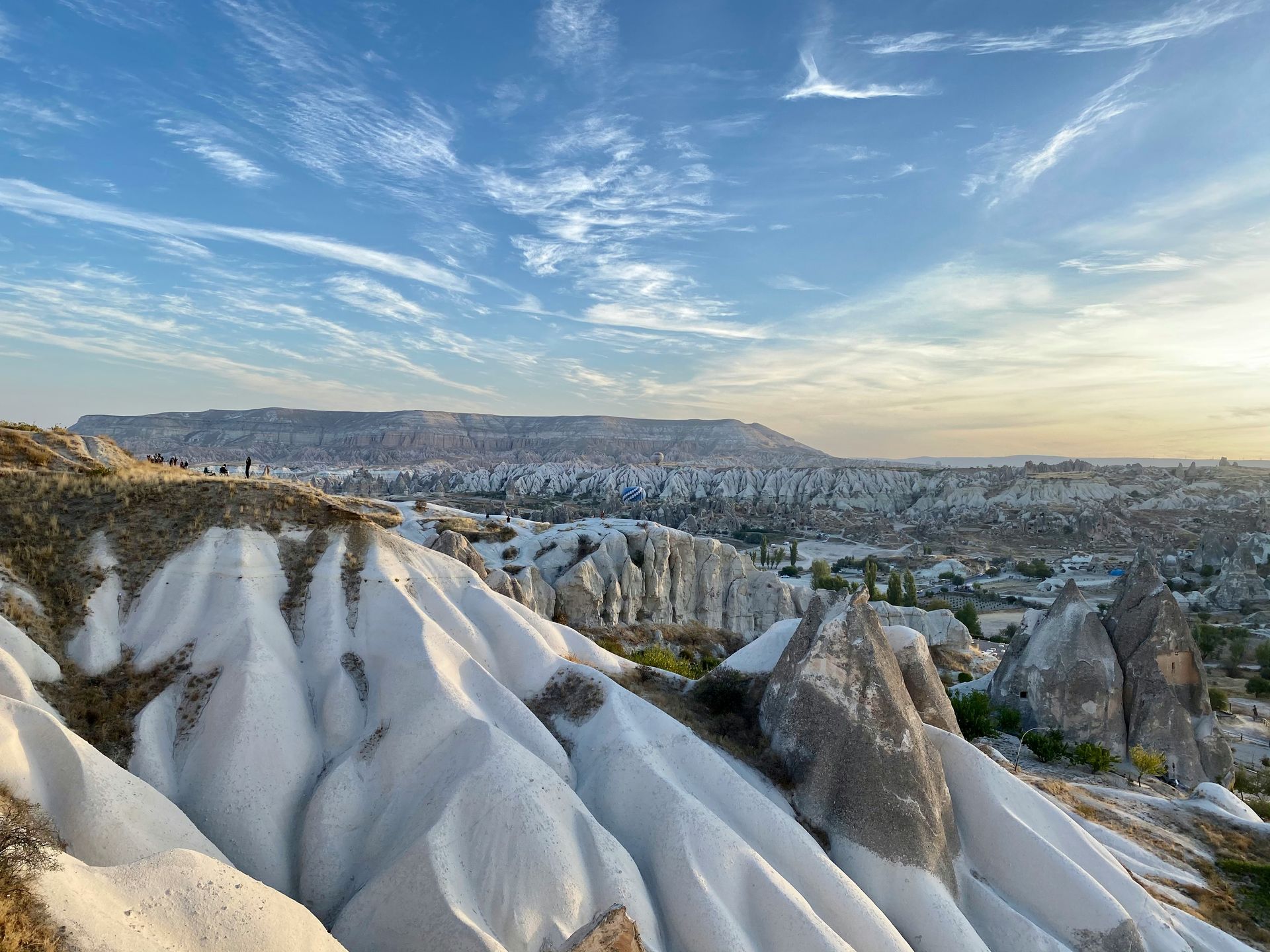 White rock formations in Cappadocia, Turkey, under a blue sky with streaky clouds.