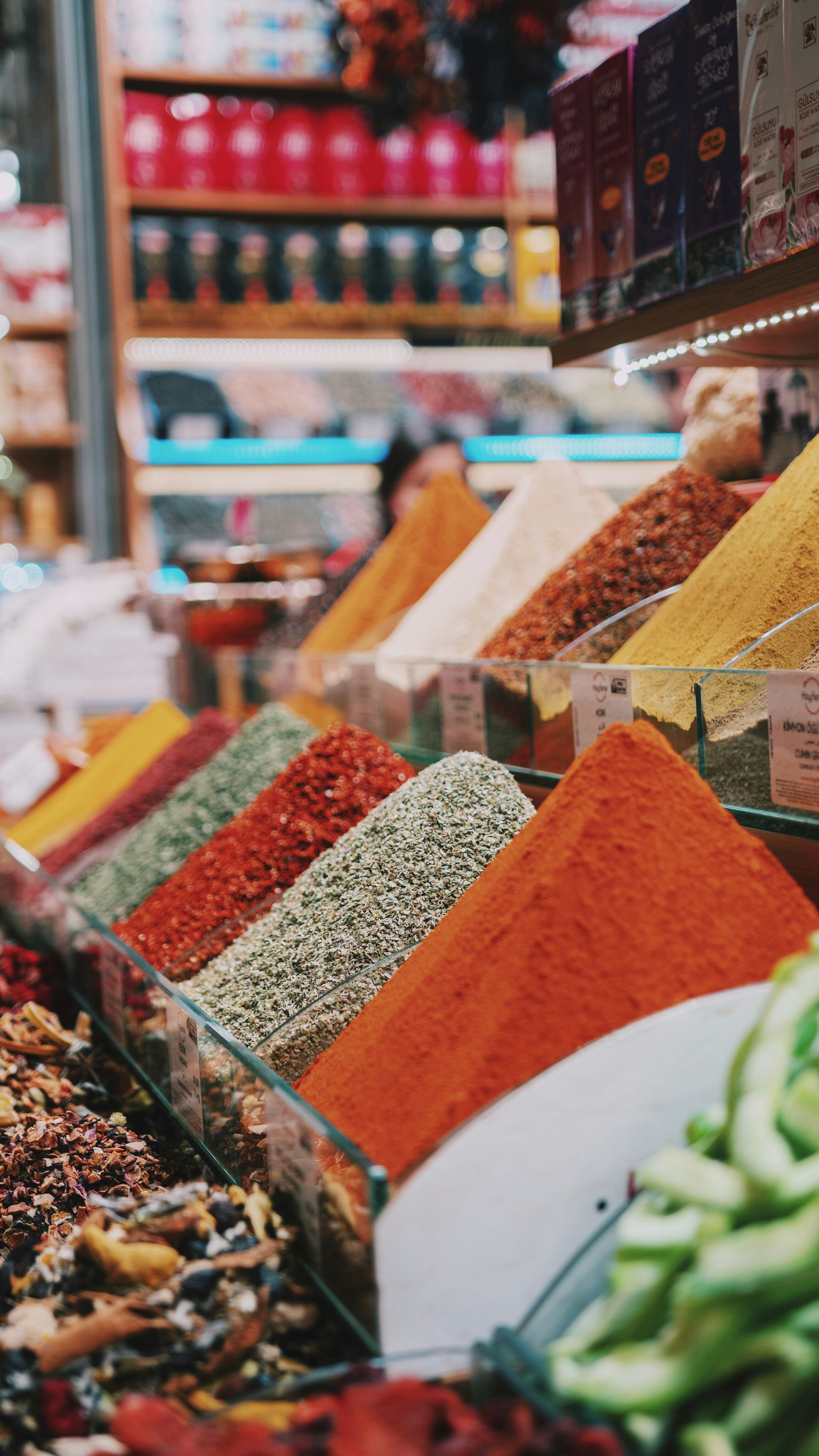 Spices in various colors displayed in glass containers at a market stall.
